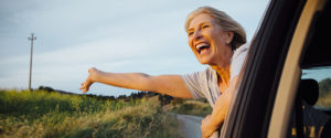 Older woman sticking her self out of car window, smiling